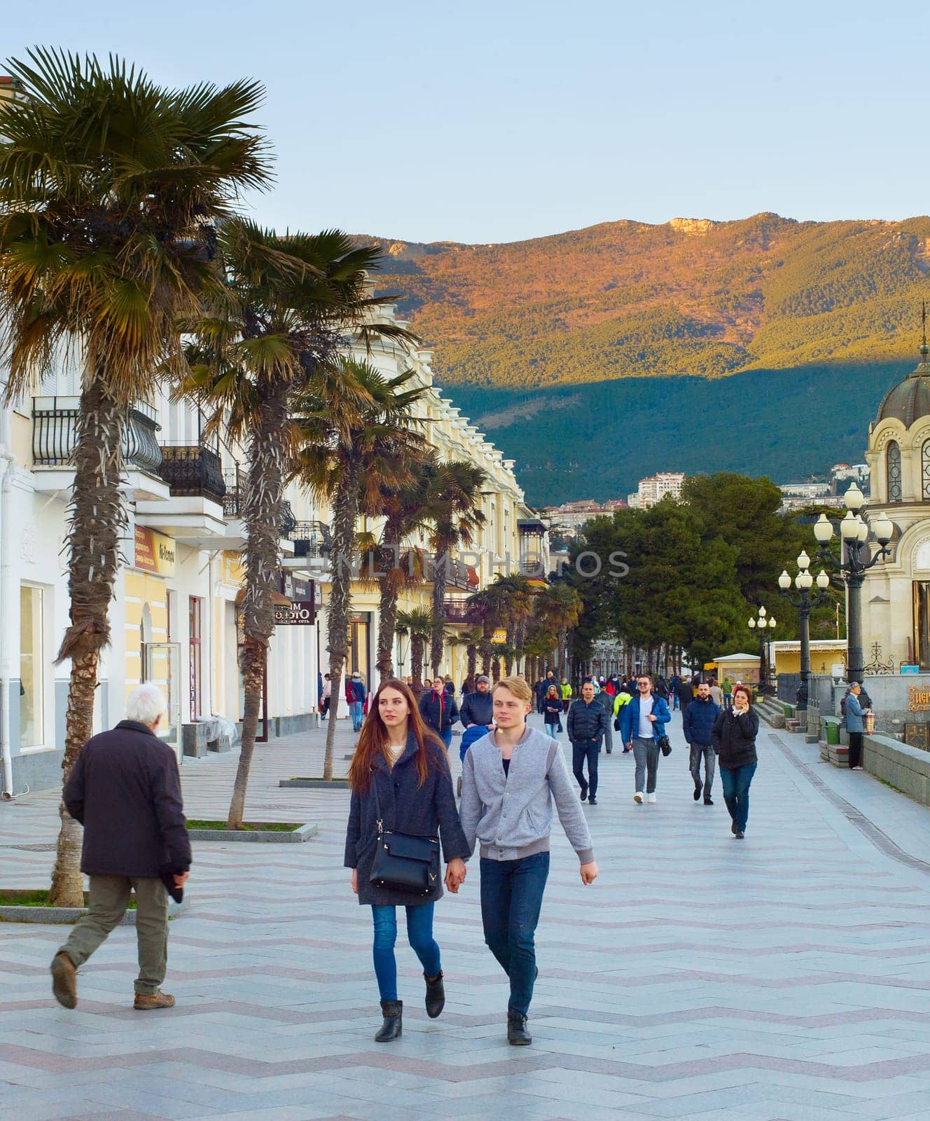 YALTA, CRIMEA, UKRAINE - APRIL 03, 2018: Couple walking by Yalta promenade at sunset. Yalta is the most famous tourist destination in Crimea