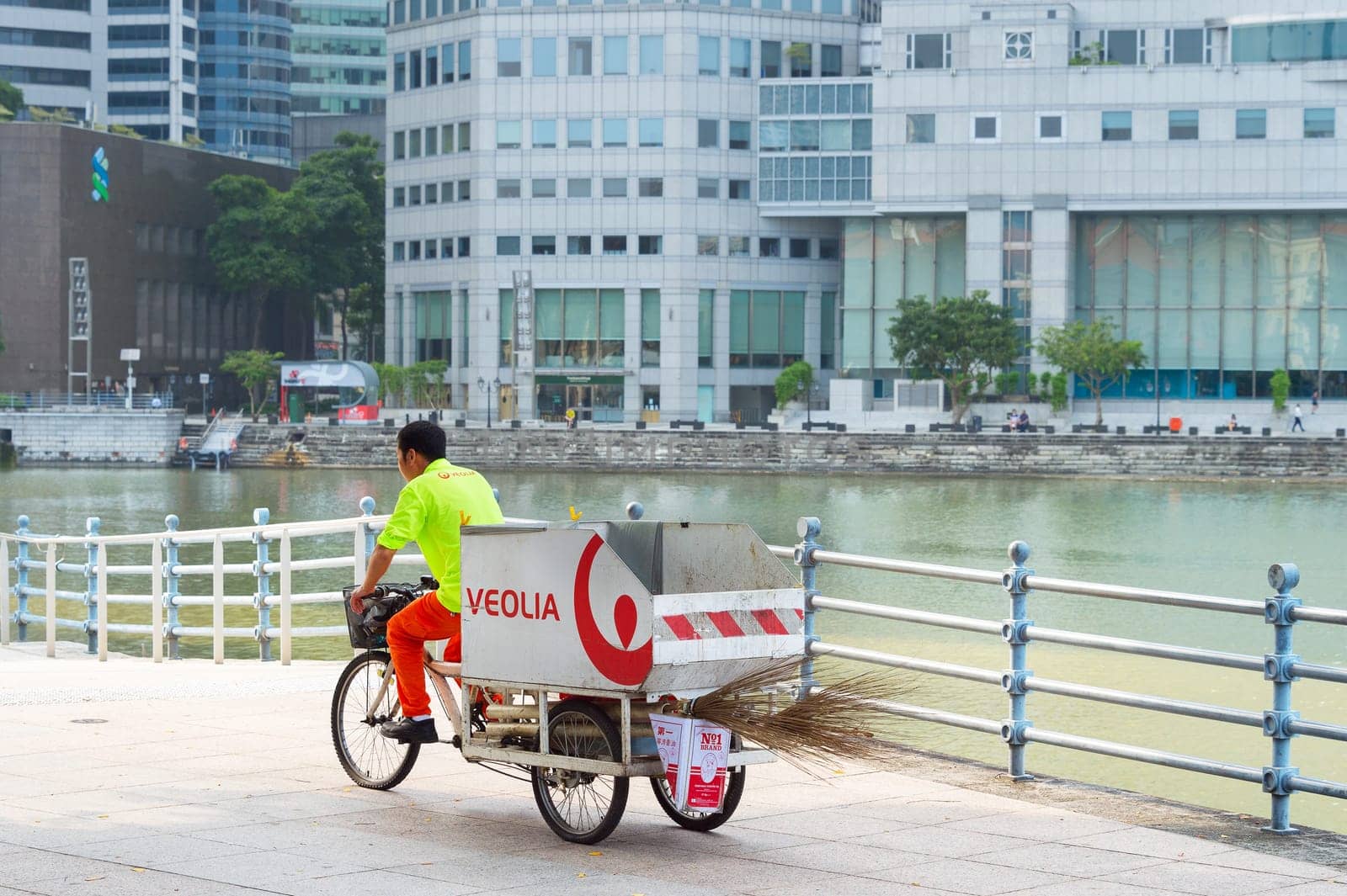 Garbage man service worker riding on bicycle carriage by Singapore downtown embankment