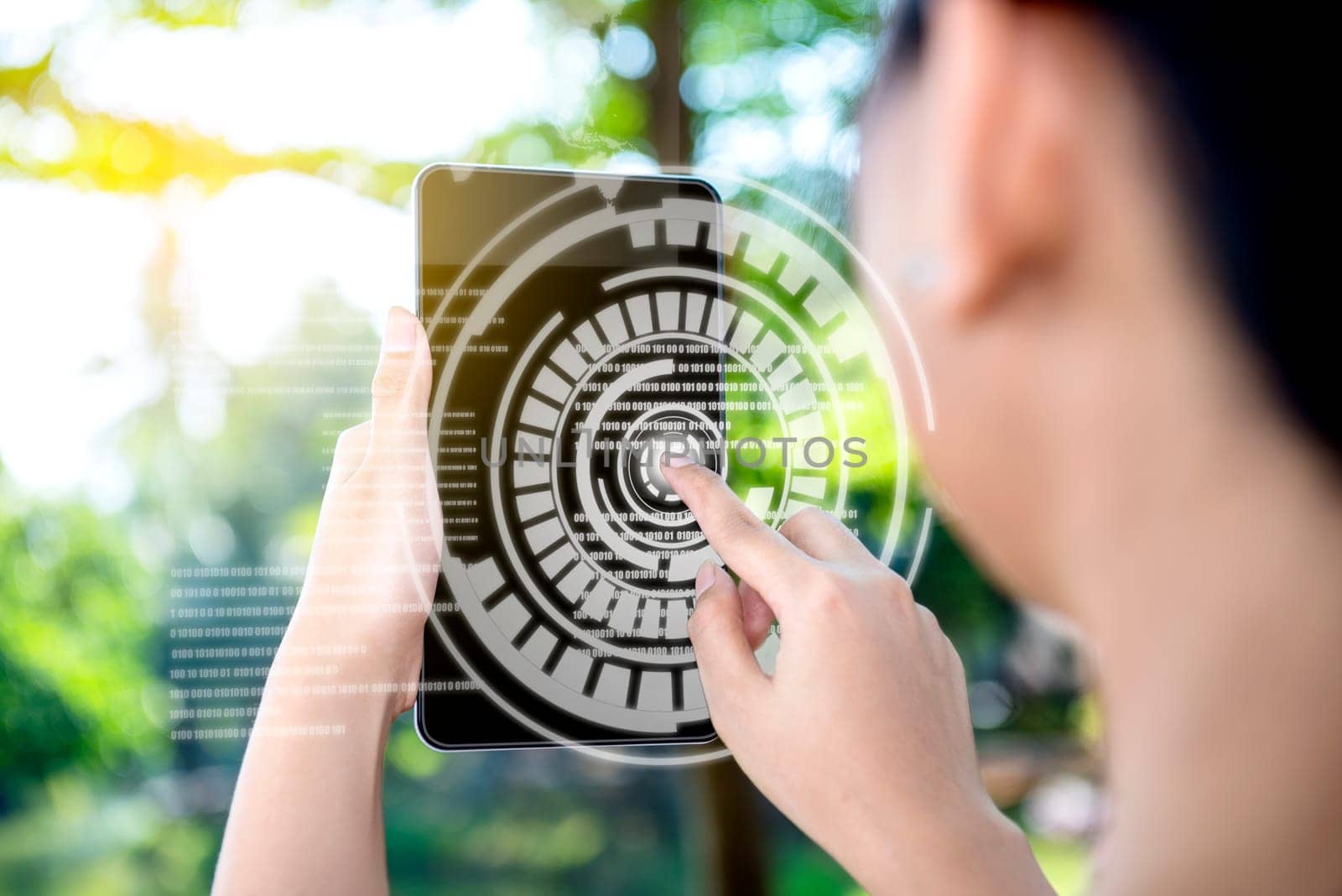Rear view of business woman touch a circle in virtual screen on the digital tablet which display the interface of world map and binary code on the park. Digital technology concept