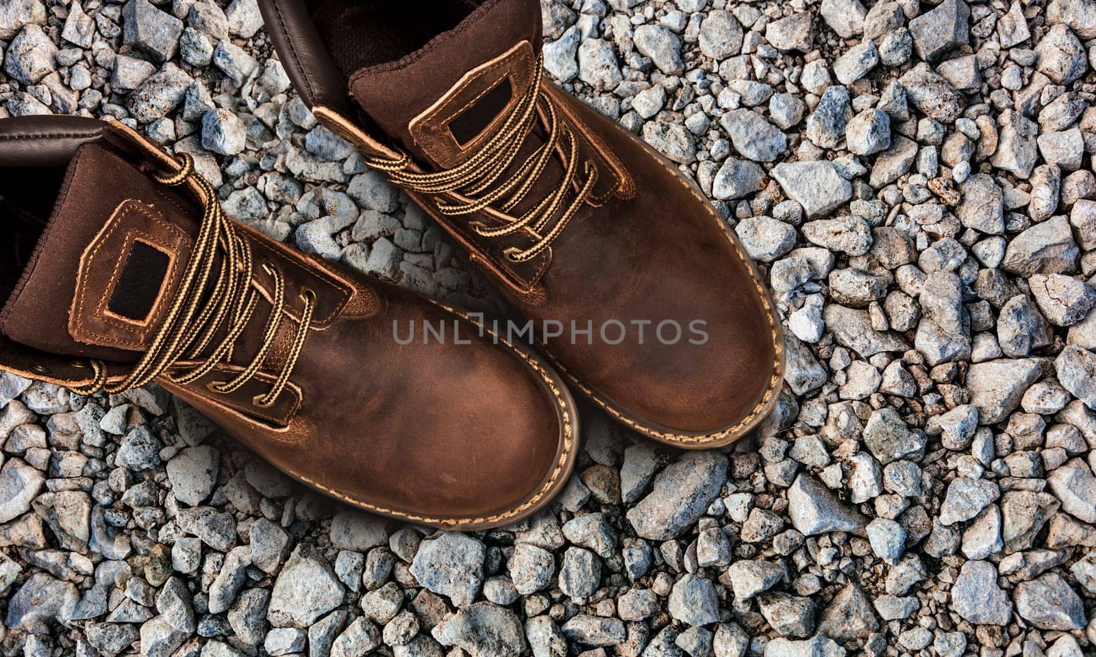 Men's brown boots on stone gravel background. Closeup isolated