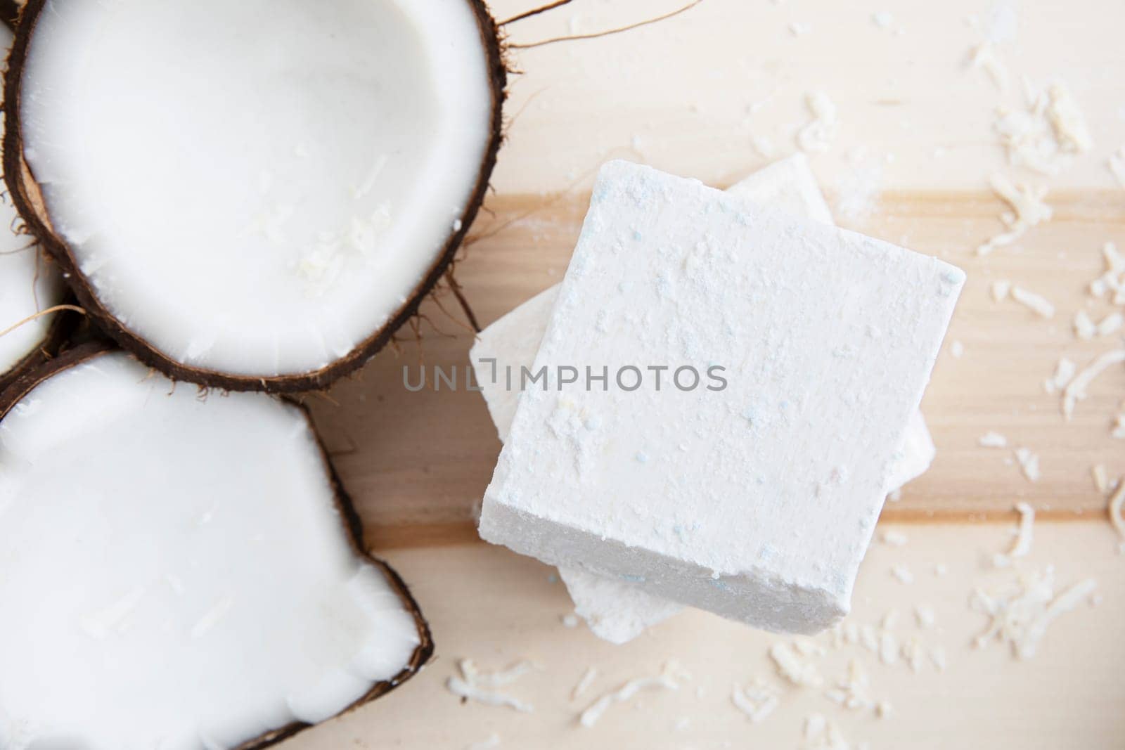 Coconut pieces and two bars of coconut soap with a top down view.