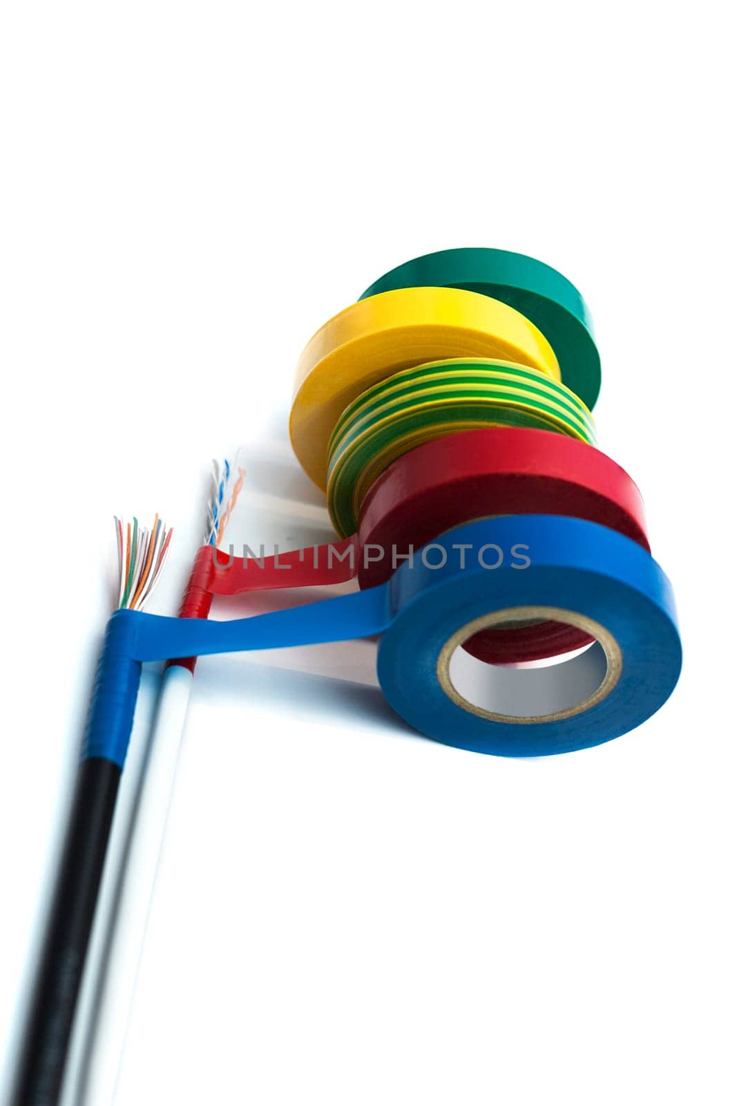 Rolls of insulation tape of different colors with the cable on white background. Blurred concept