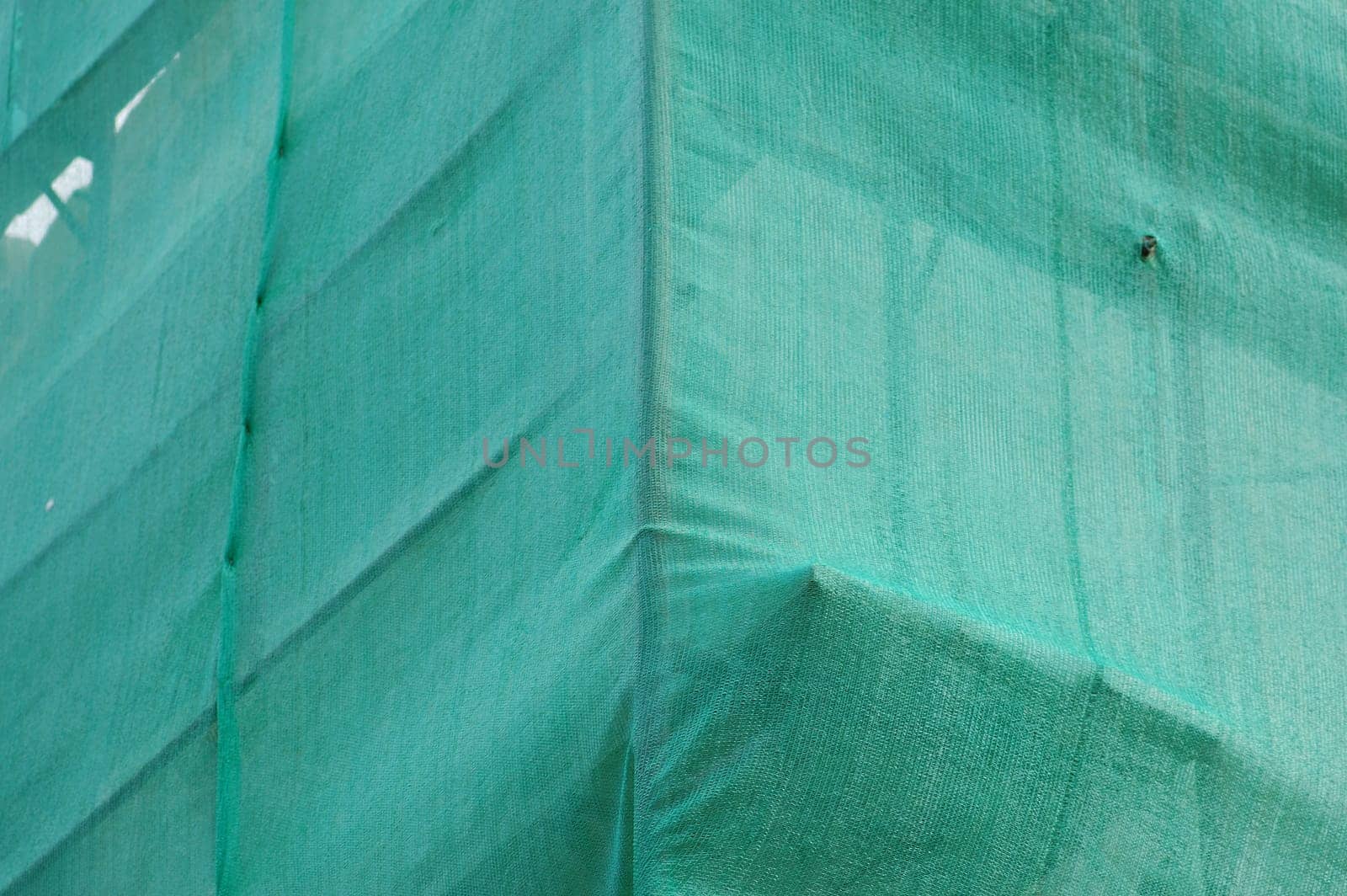 Under construction building covered with green debris netting.