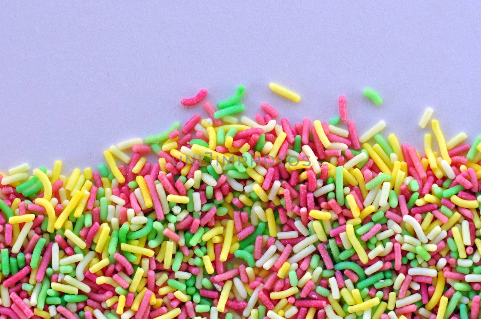 Colorful candy sprinkles garnish sweet food topping on white background.
