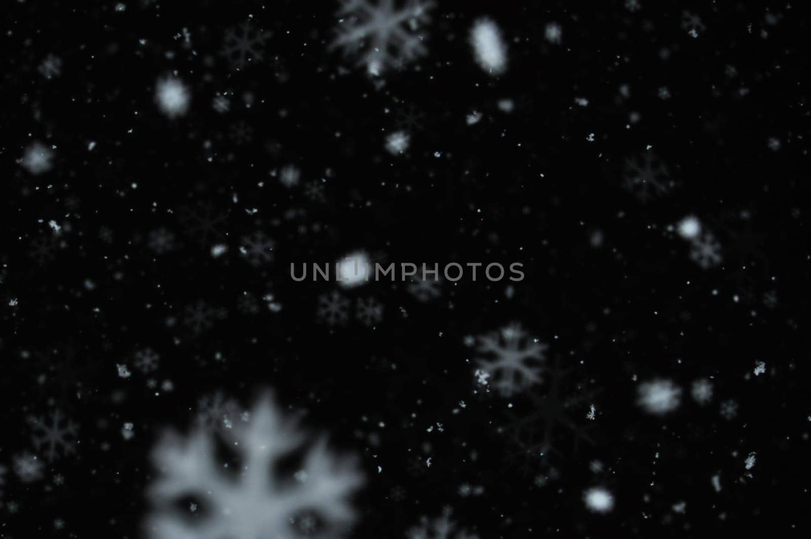Snow on night sky abstract blur background. Snowflakes bokeh effect.