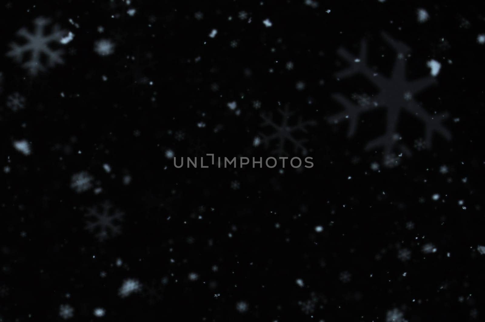 Snow falling on cold winter night. Snowflakes bokeh blur effect abstract background.