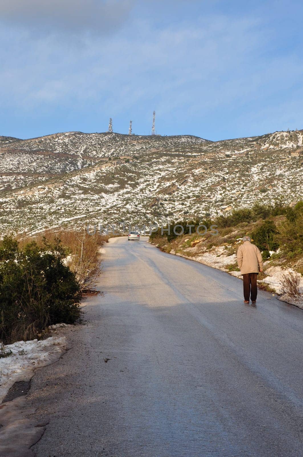 ATHENS, GREECE - JANUARY 4, 2015: Man walking on Penteli mountain in Athens, Greece. Snow melting on sunny winter day.