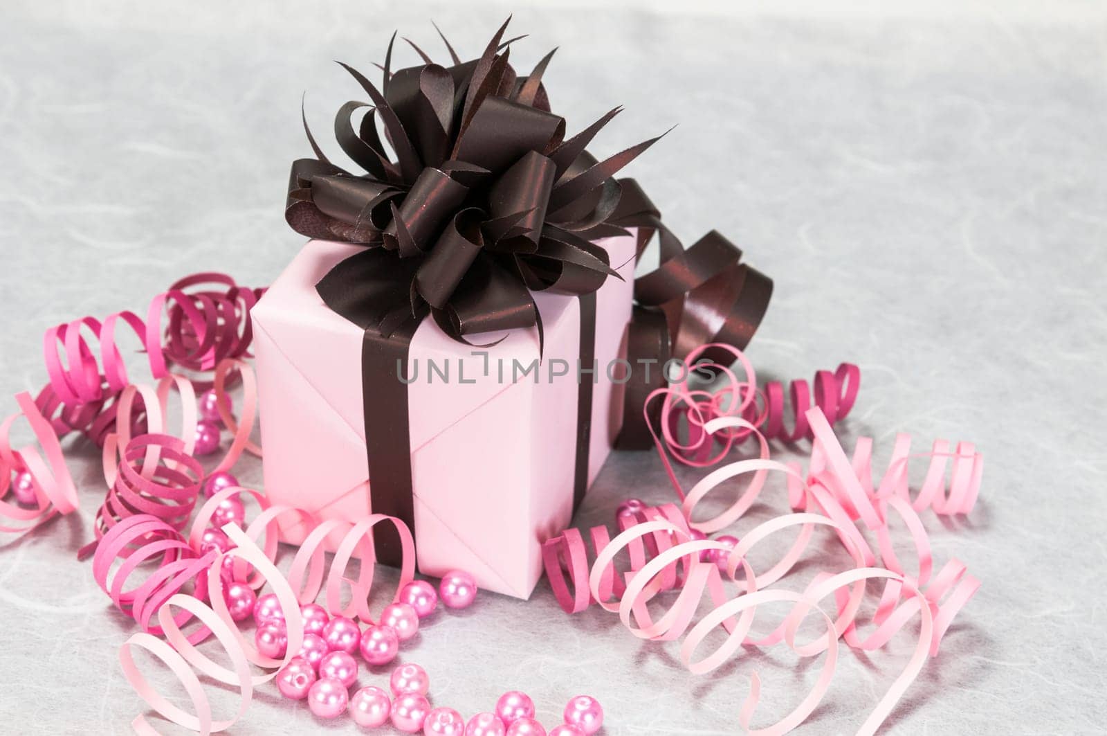 Gift pink box with ribbons, beads and a brown bow