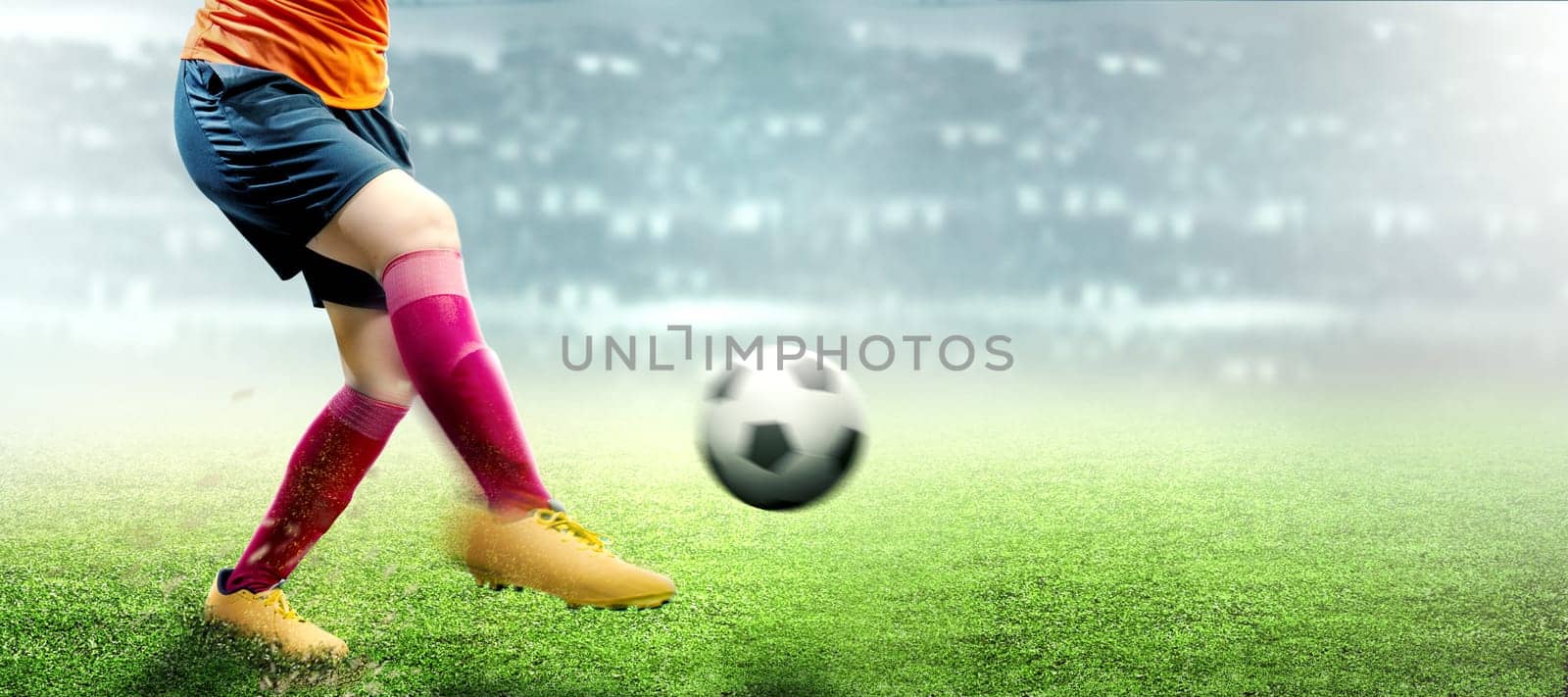Football player woman in orange jersey kicking the ball on the football field