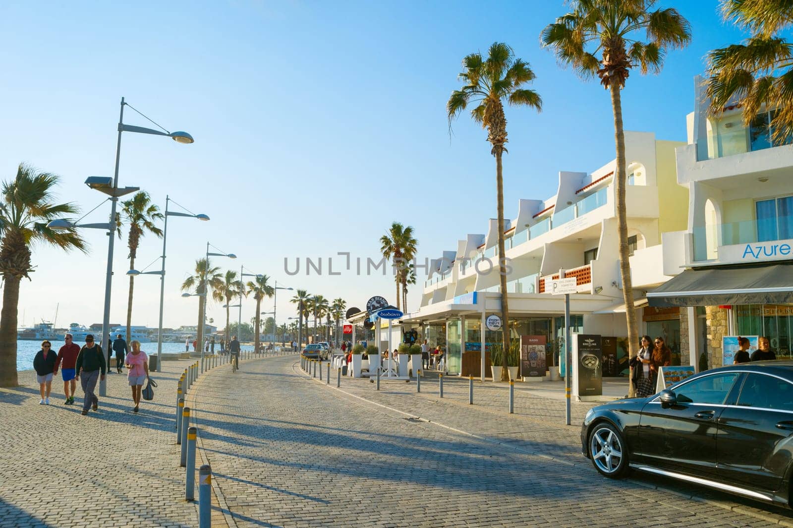 PAPHOS, CYRPUS - FEBRUARY 13, 2019: People walking by Cyprus promenade at sunset. Paphos - famous tourist destination in Cyprus