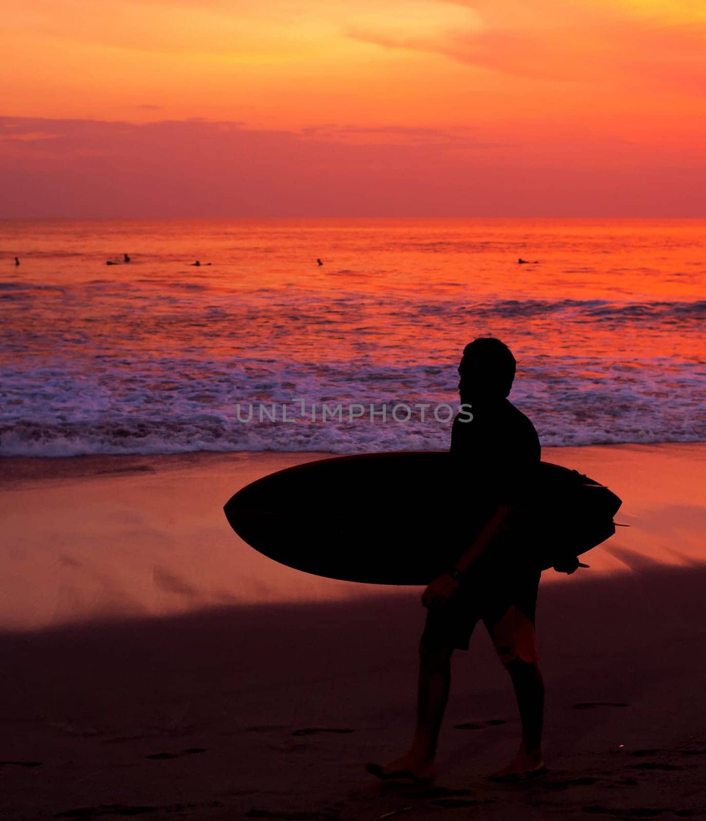 Surfer with surfboard walking by the ocean beach. Bali island, Indonesia