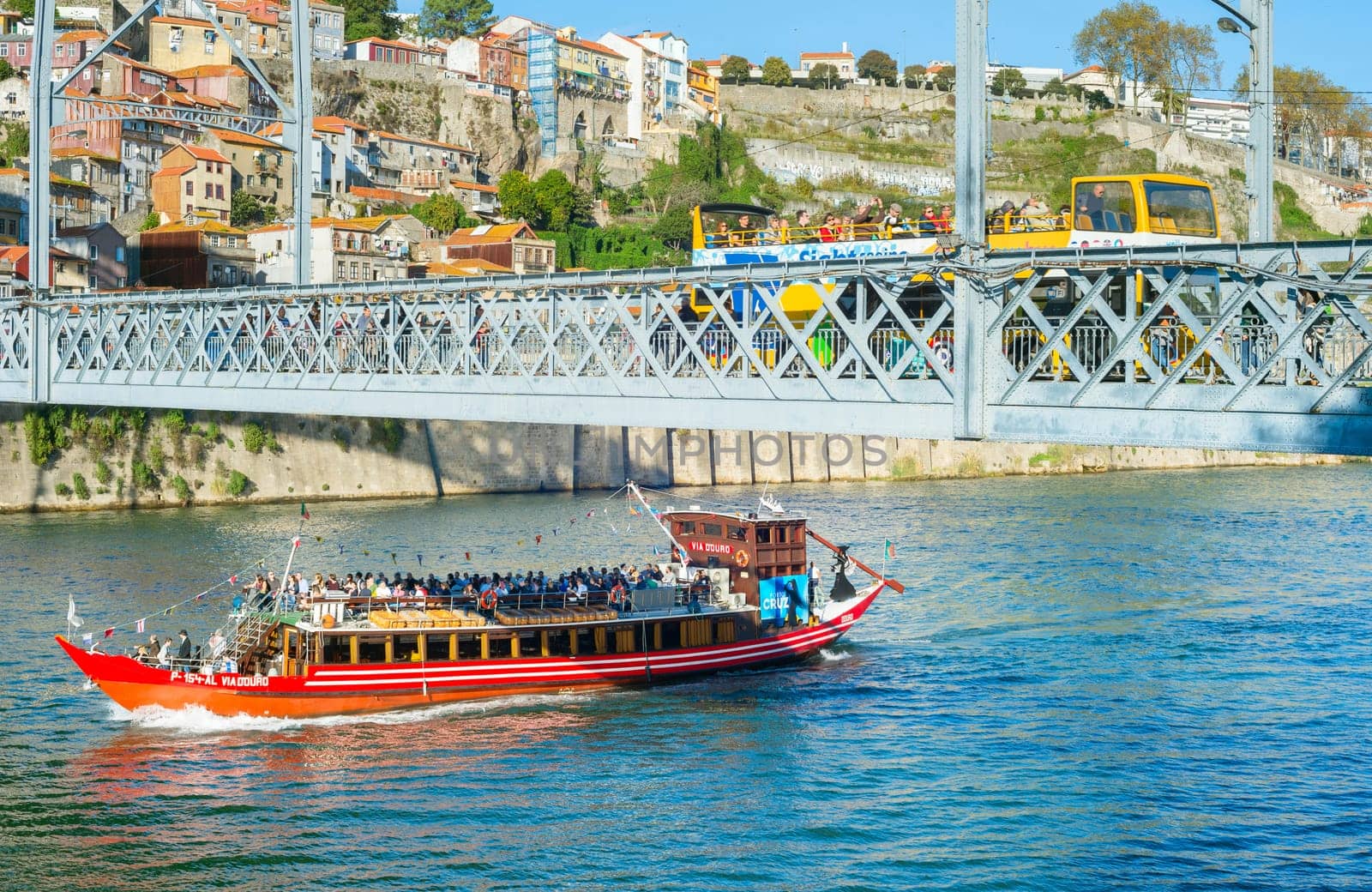 PORTO, PORTUGAL - NOVENBER 13, 2016: Tourist boat passing under Dom Luis Bridge with yellow tour bus, Porto, Portugal