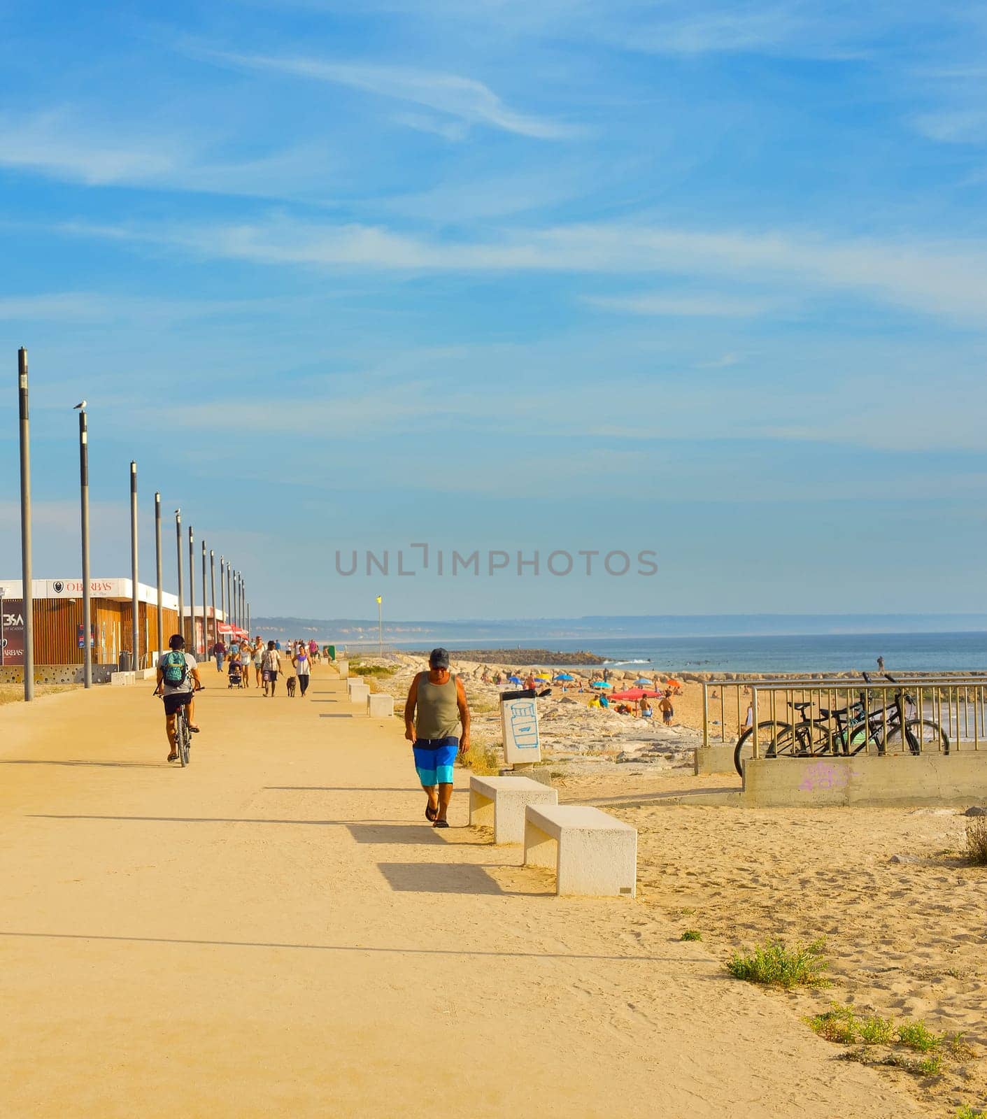 COSTA DA CAPARICA, LISBON, PORTUGAL - SEPTEMBER 17, 2018: People walking by seaside promenade in the sunny summer day. Costa de Caparica is the famous tourist destination