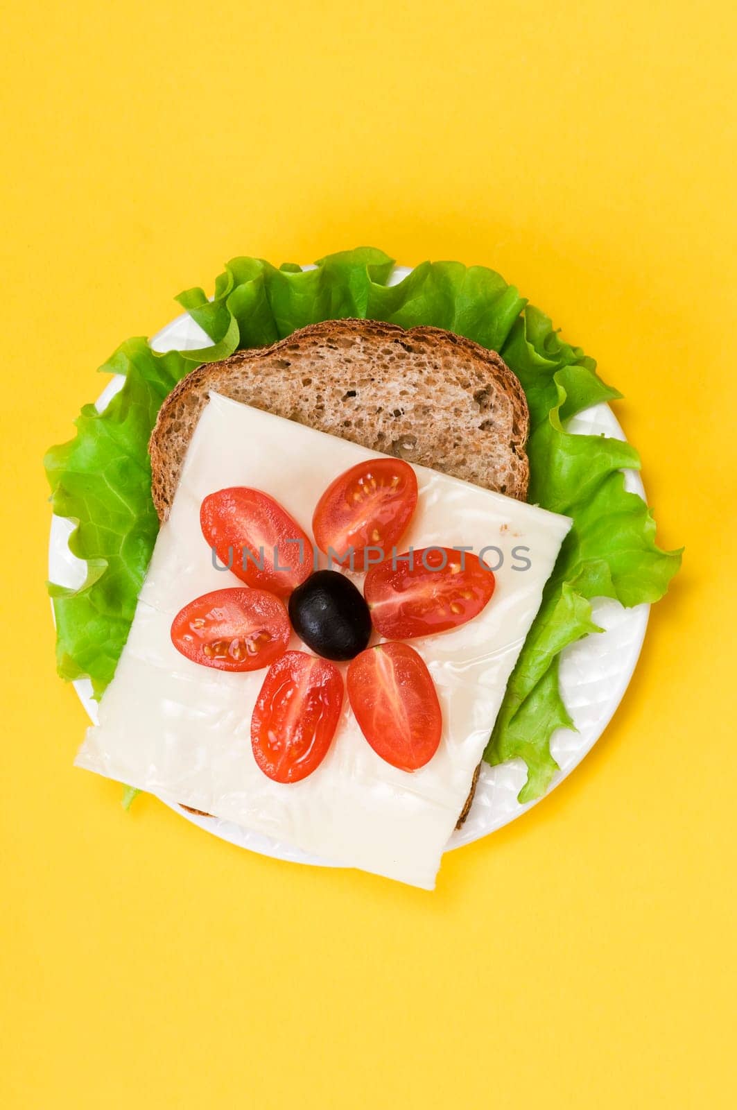 sandwich with vegetables on a white plate on a yellow background