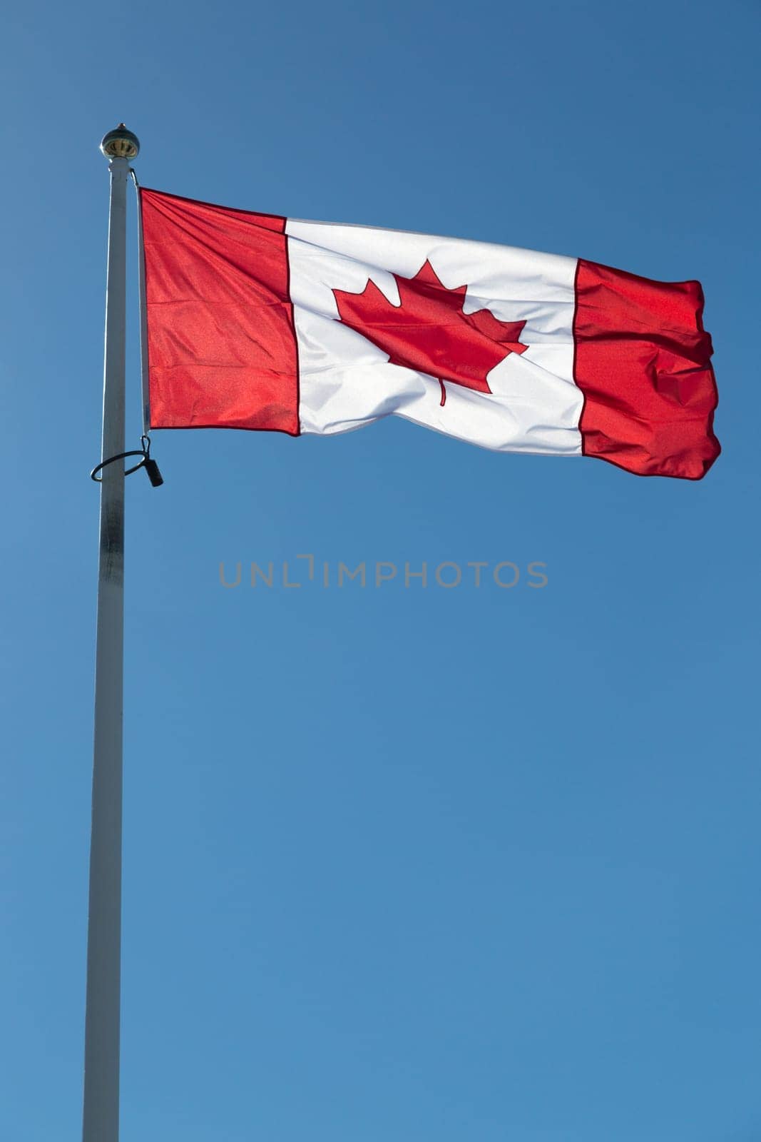The Canadian Flag on a Falgpole with a clear blue sky.