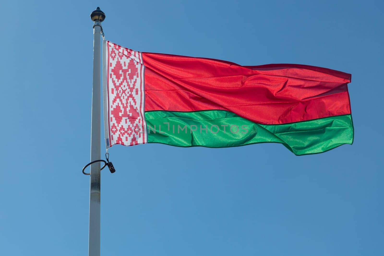 The Flag of Belarus close up with a blue sky.