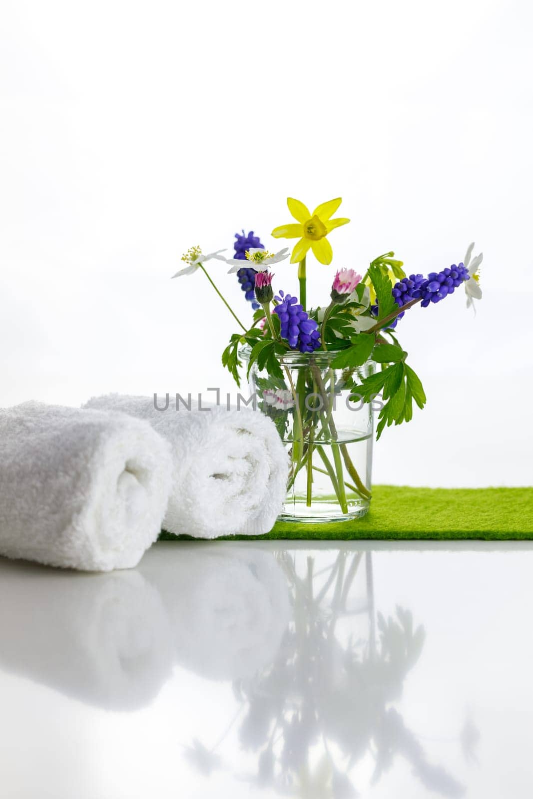 White towels with heart on a white background with flowers in a vase. Spring.
