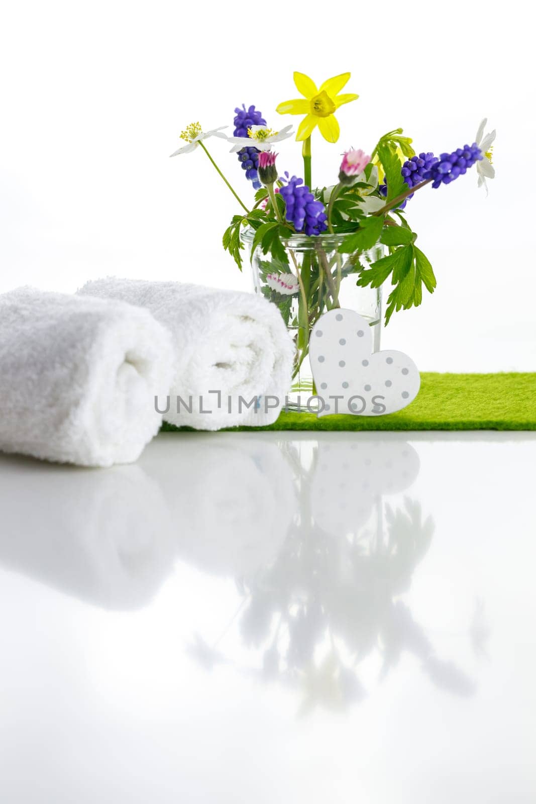 White towels with heart on a white background with flowers in a vase. Spring.