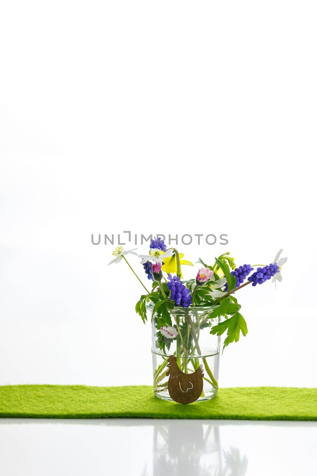 White towels next to a cream tin against a white background and flowers in a vase. Spring. Easter bunny.