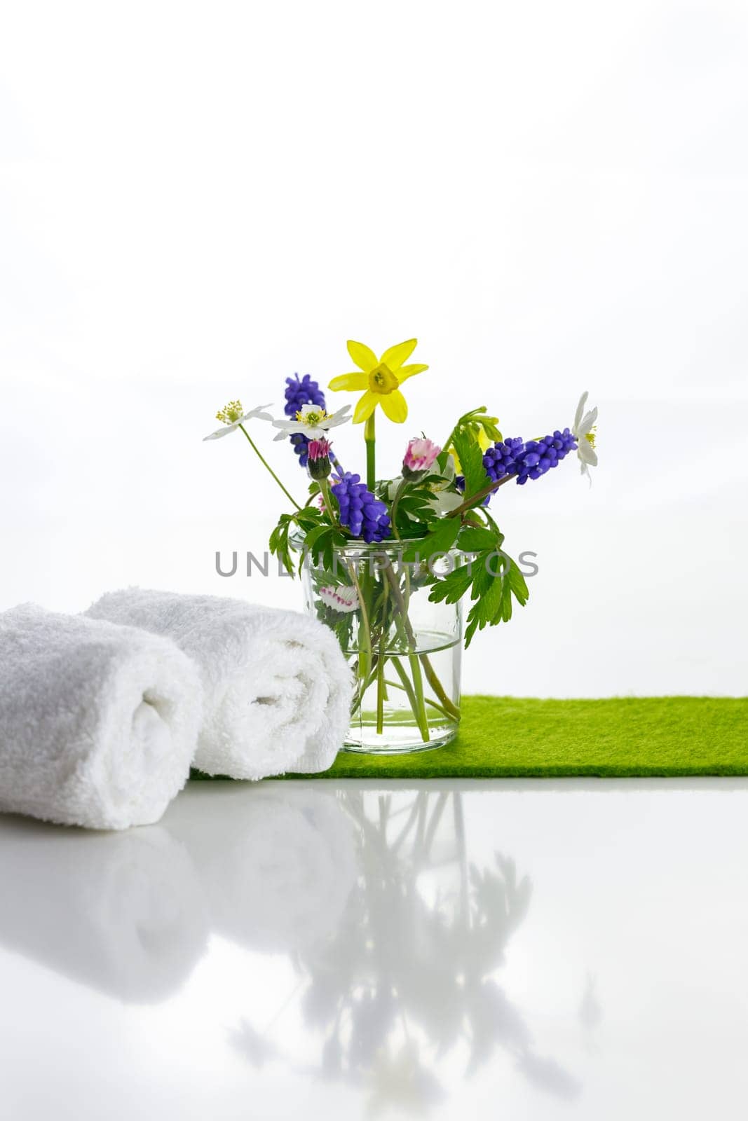 White towels with heart on a white background with flowers in a vase. Spring.