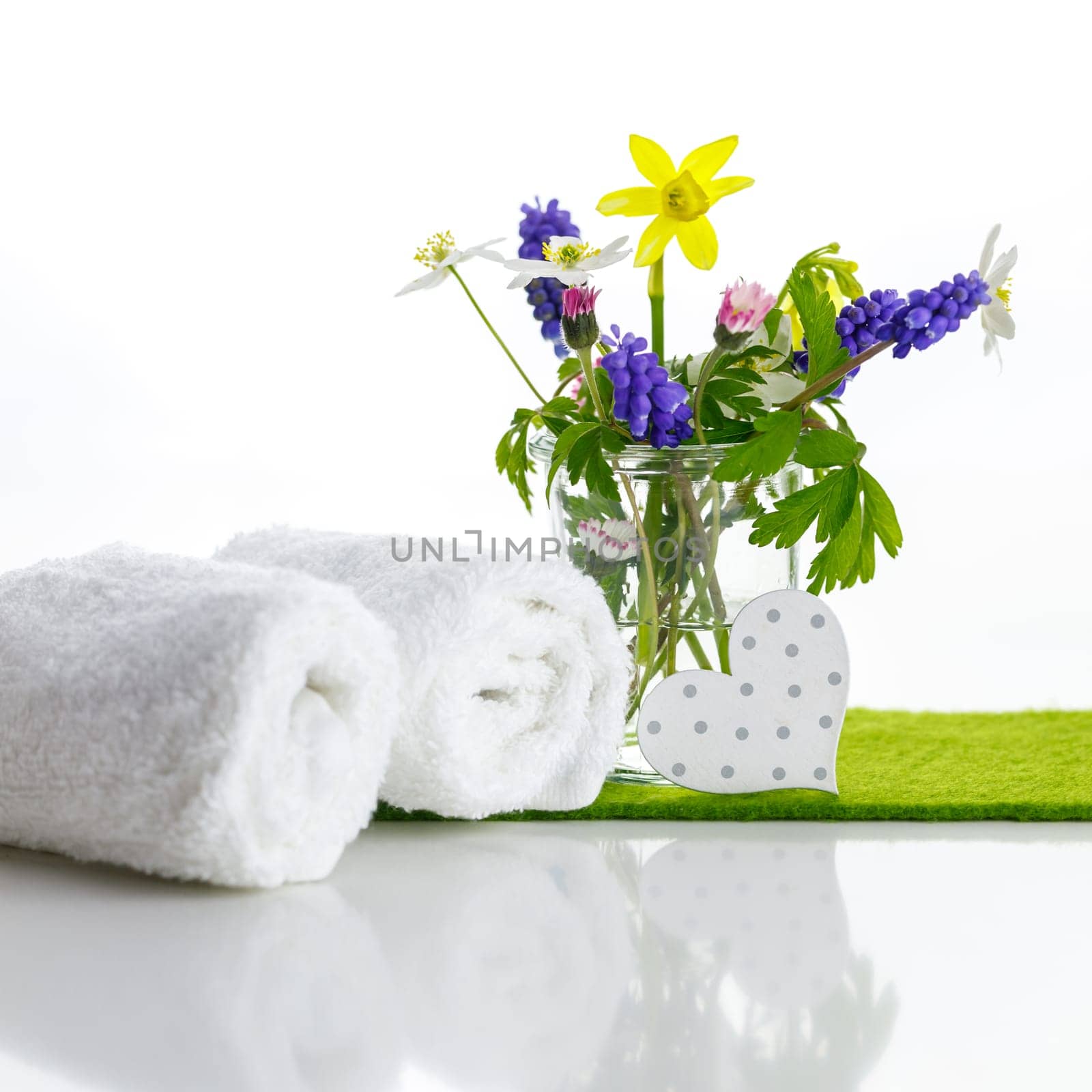White towels with heart on a white background with flowers in a vase. Spring.