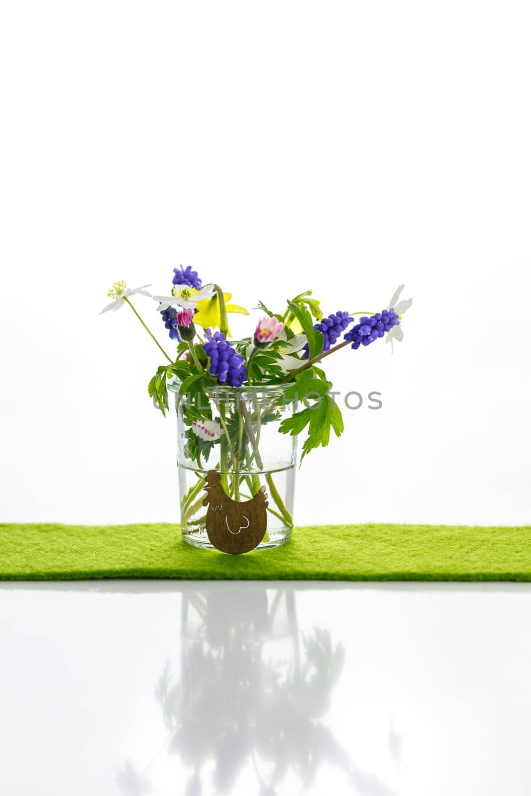 White towels next to a cream tin against a white background and flowers in a vase. Spring. Easter bunny.