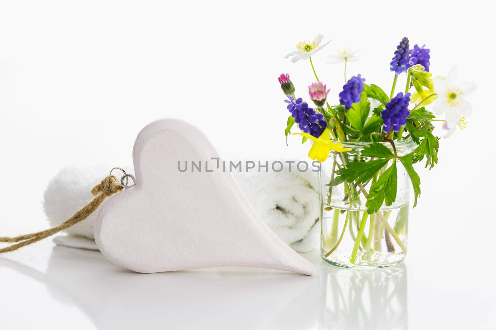 White towels with heart on a white background with flowers in a vase. Spring.