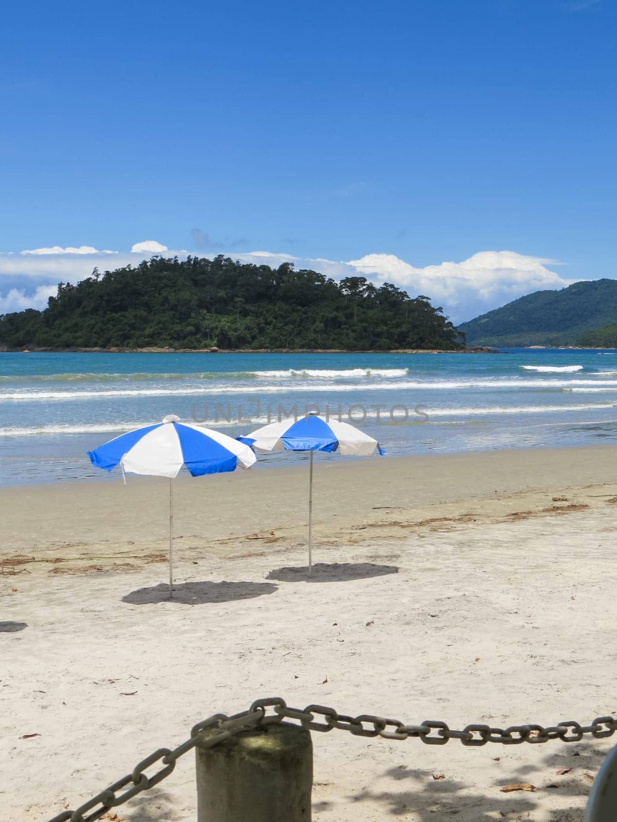 View of seaside in sunny day, with blue sky, and chains in the foreground.