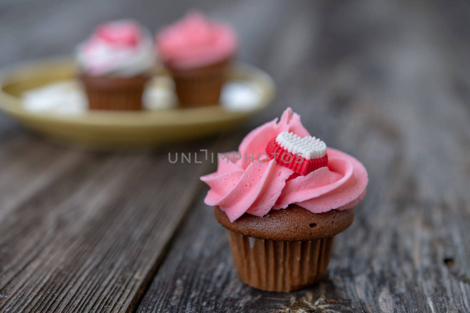 pink and white muffins on wooden ground with heart whipping cream