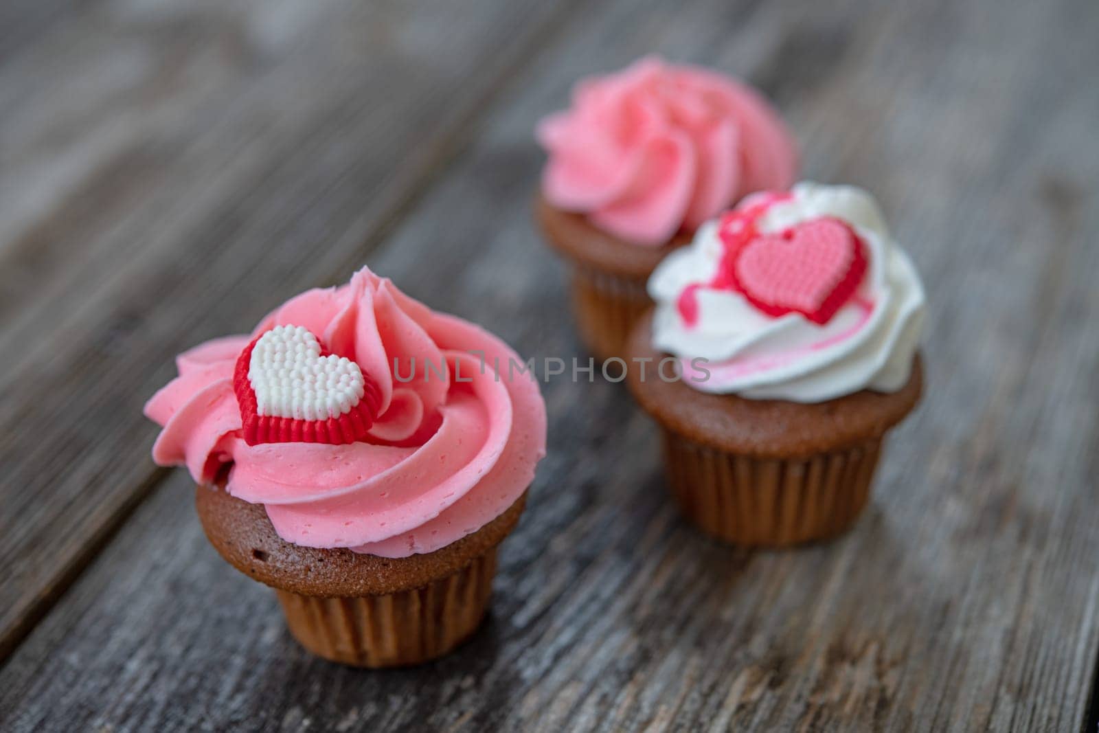pink and white muffins on wooden ground with heart whipping cream