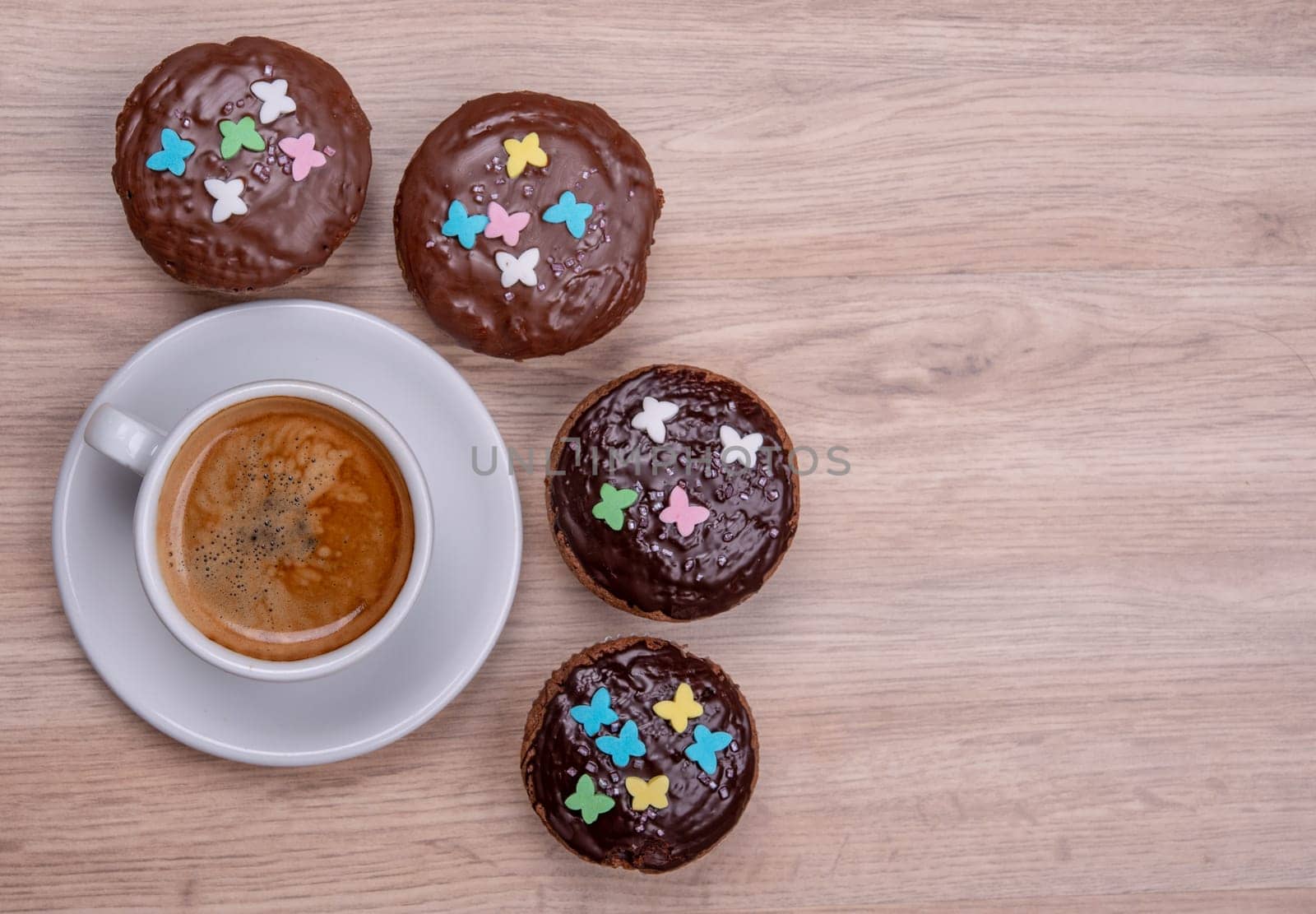 chocolate muffins with cup of coffee on wooden ground