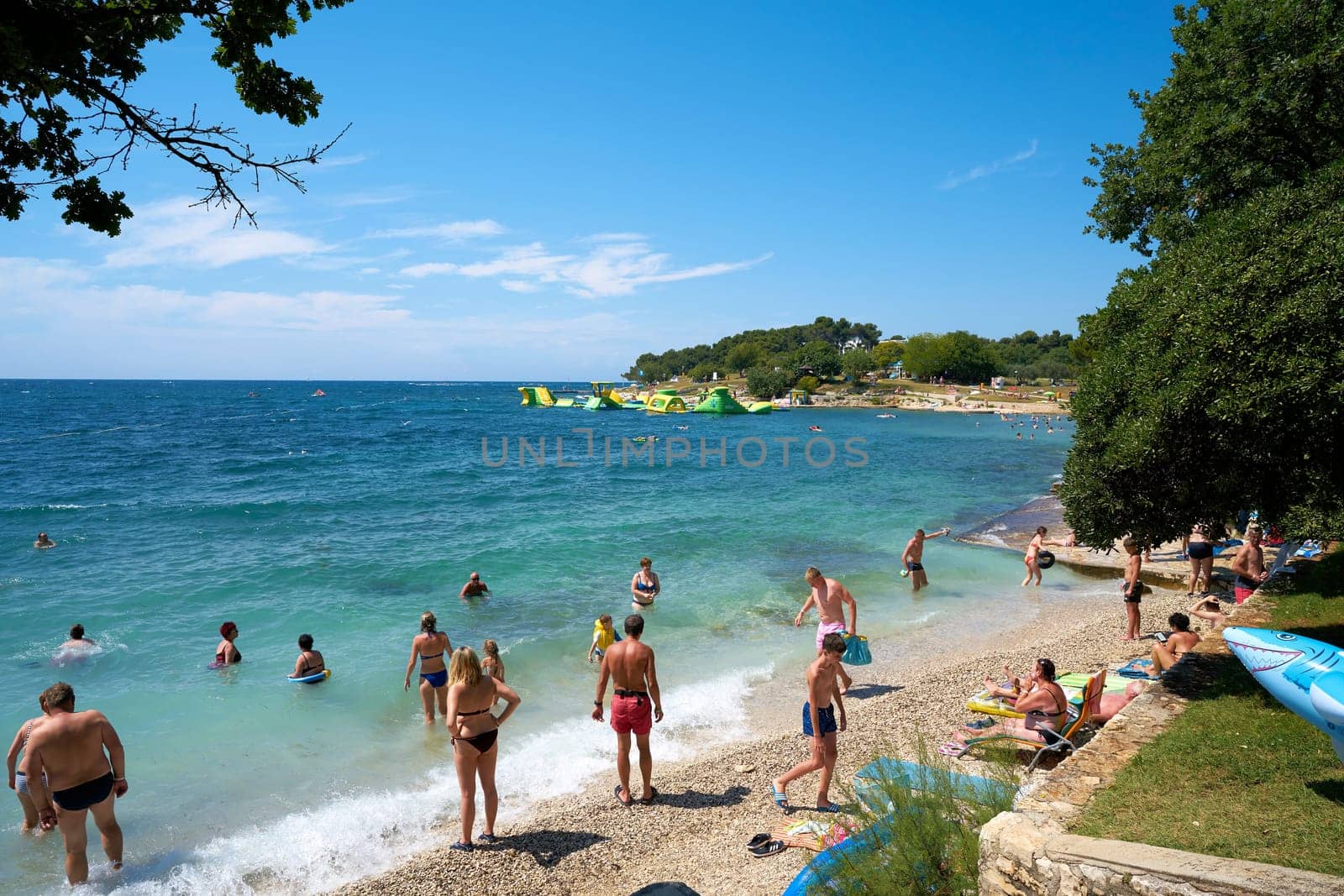 Tourists and holidaymakers on the beach of the Adriatic Sea near Porec in Croatia
