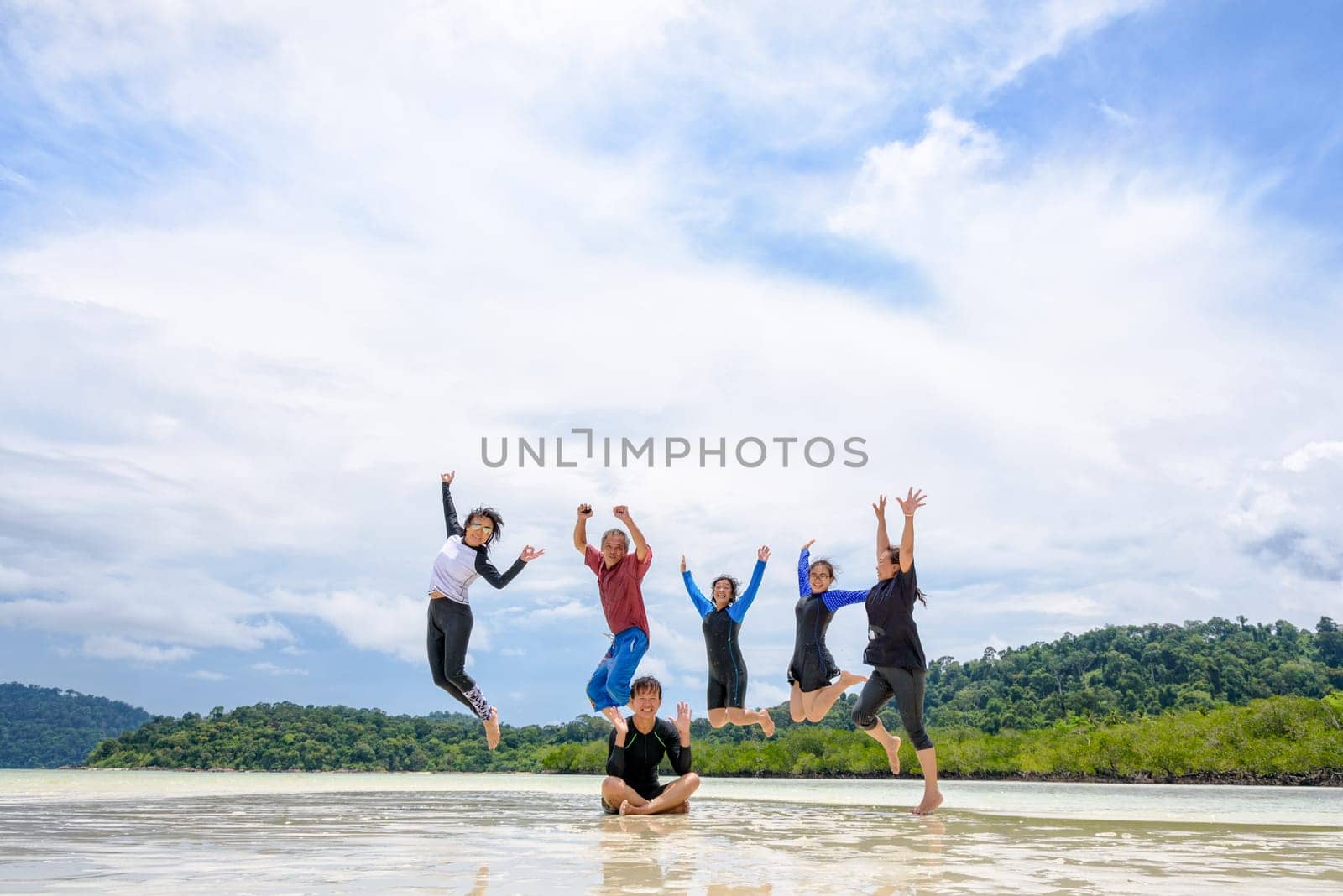 Asian traveler group adult and teens are family, Happy life enjoy by play jumping together at the beach on blue sky background, vacation in summer holiday at Ko Lipe and Ra Wi island, Tarutao, Thailand