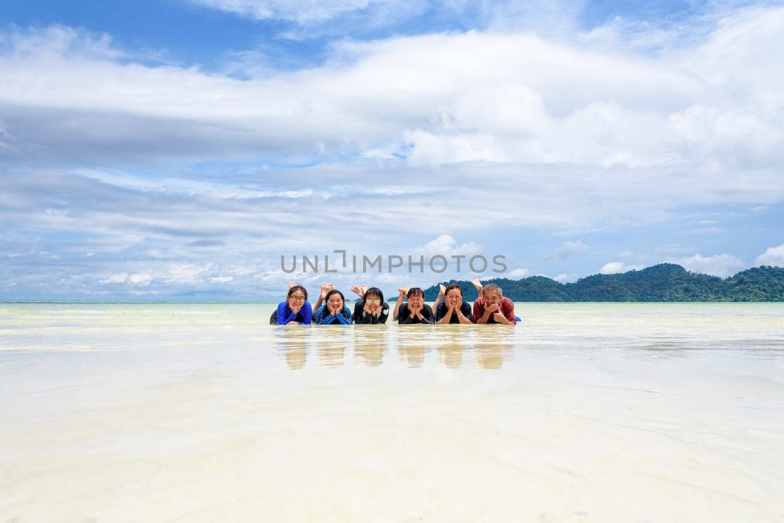 Asian people group adult and teens are family, Happy life enjoy by lying together on the beach of Ra Wi island during the sea travel vacation in summer holiday at Ko Lipe, Tarutao, Satun, Thailand