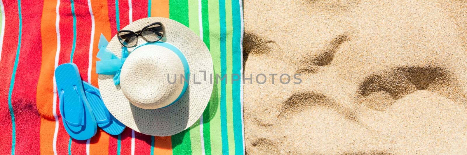 Multi colored beach towel with beach accessories on yellow sand