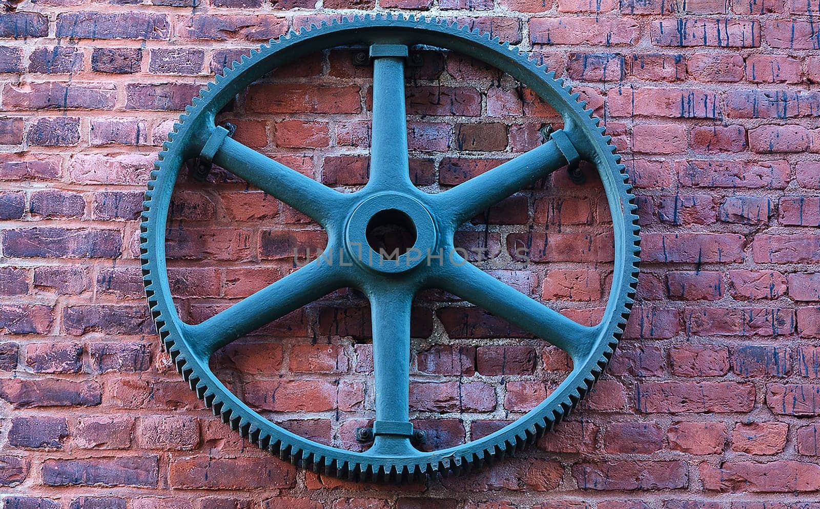 one old gear an a wall  of one hold house made of stone
