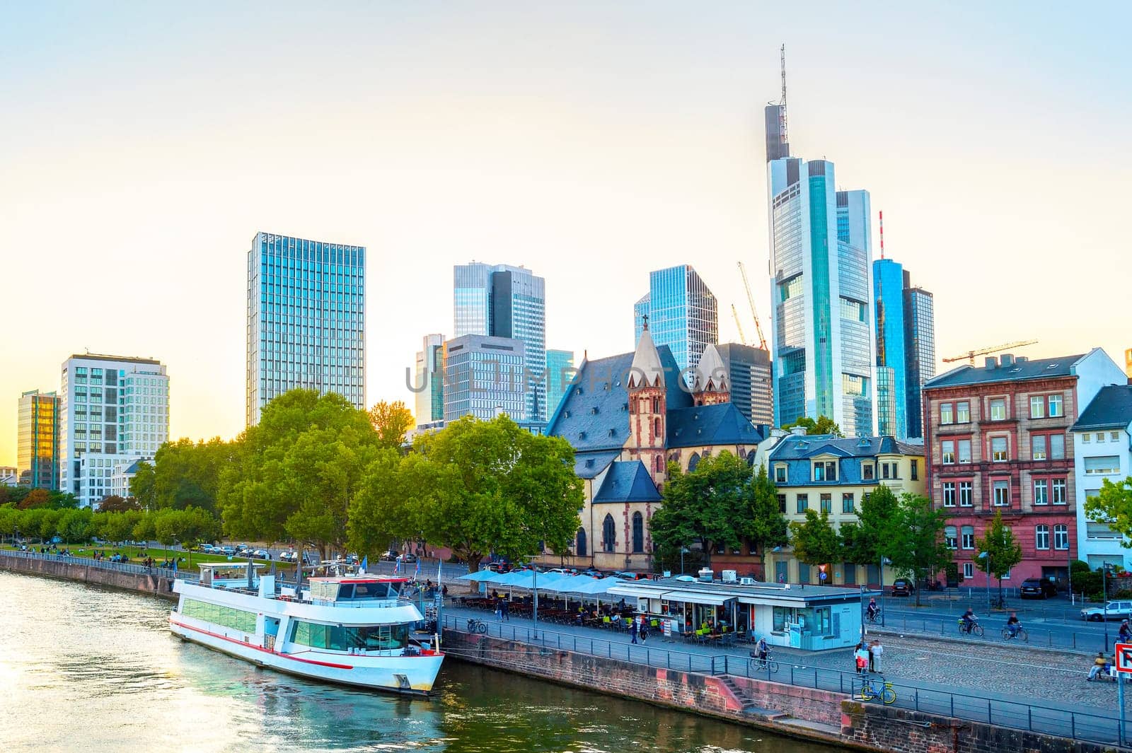 Frankfurt afterglow cityscape with modern archtecture, business district skyscrapers,  restaurants, tour boat at Main river, Germany