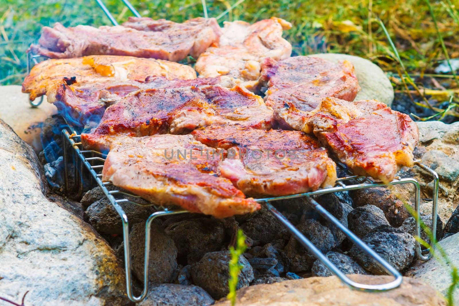 Outdoor grilling pork meat on charcoal grill fire