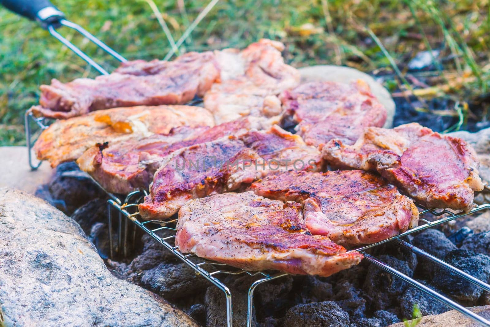 Outdoor grilling pork meat on charcoal grill fire