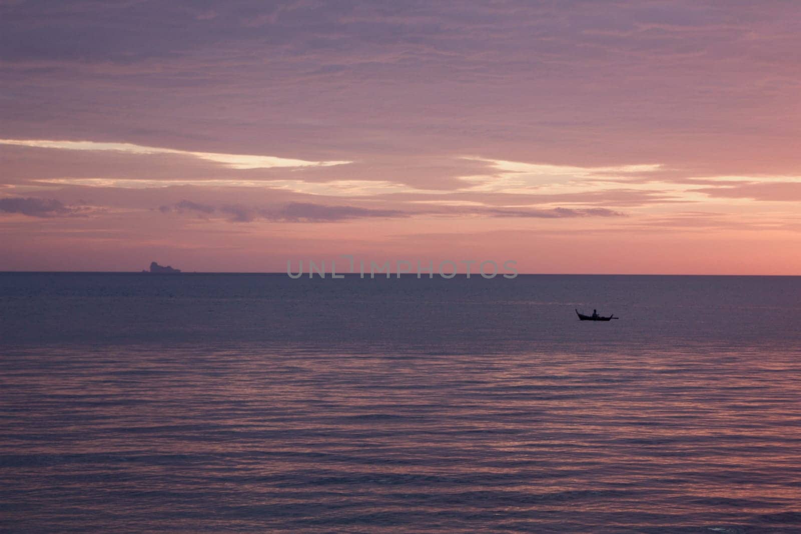 An islander paddles a dug out canoe in Thailand at sunset