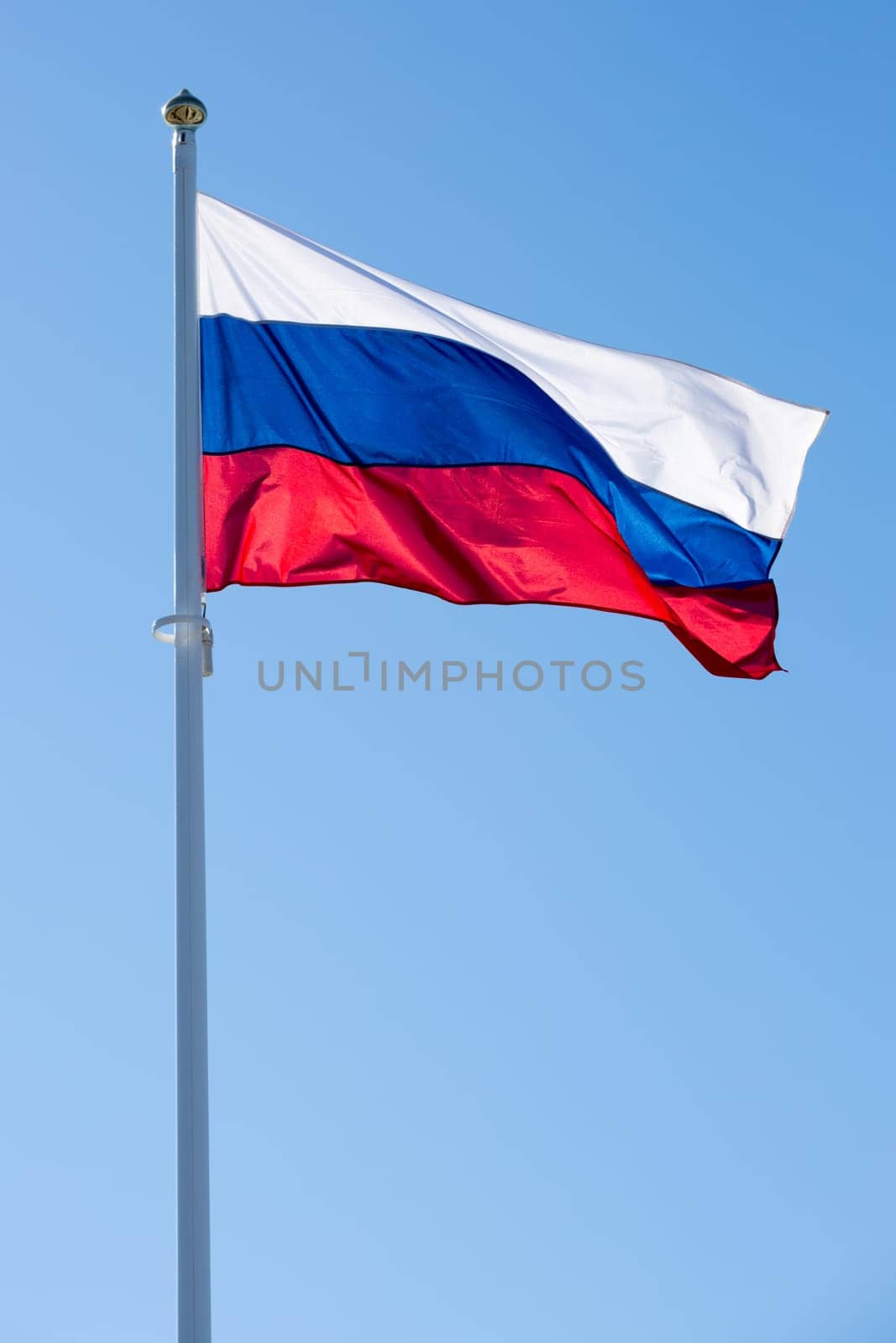 The Flag of Russia waving in the wind with a clear blue sky.