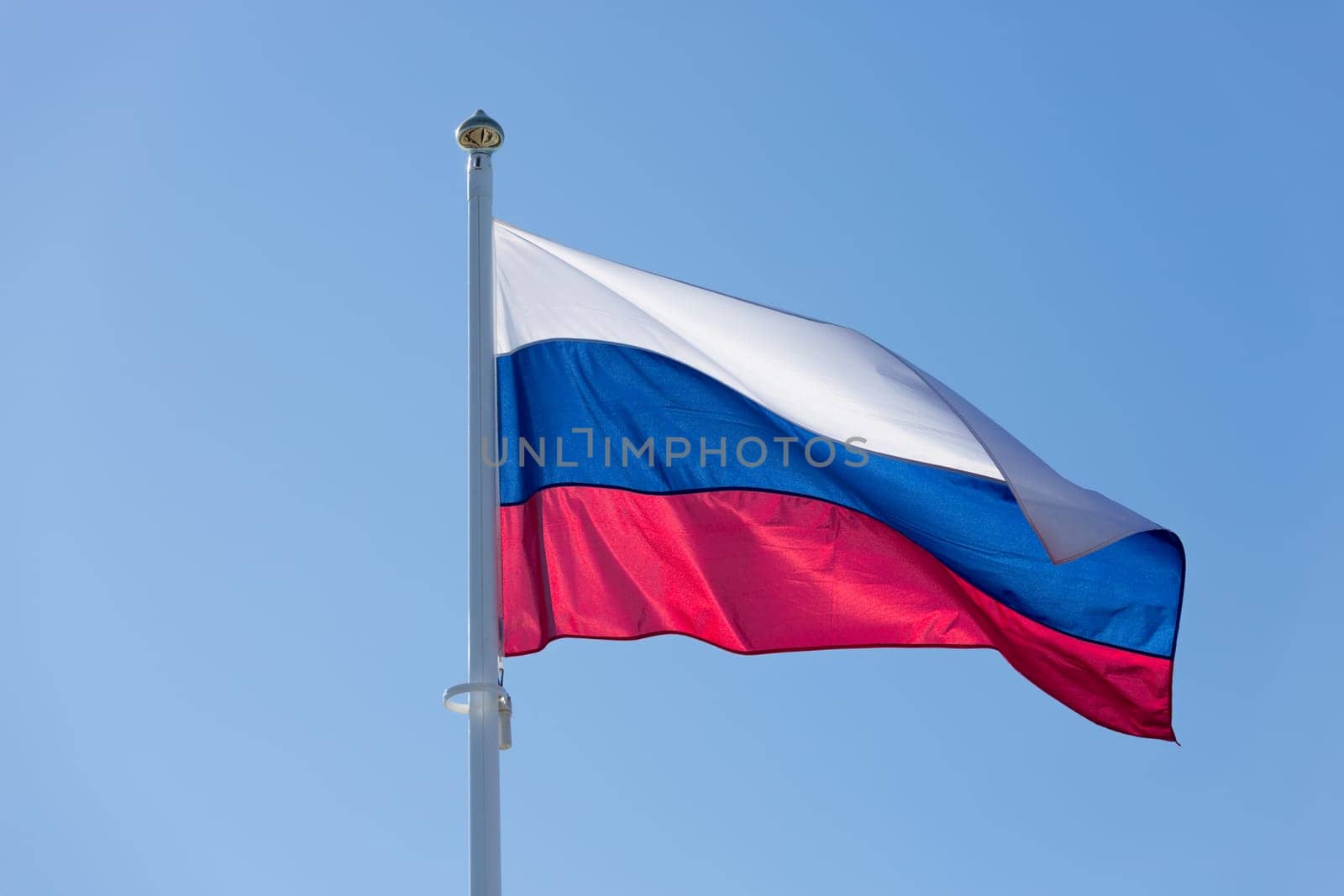 The Flag of Russia waving in the wind with a clear blue sky.