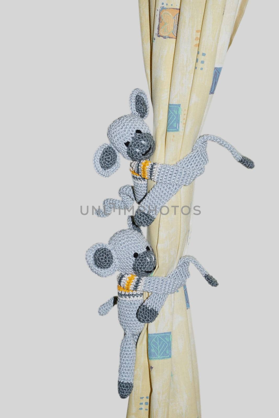 Two crocheted monkeys cling to the curtain