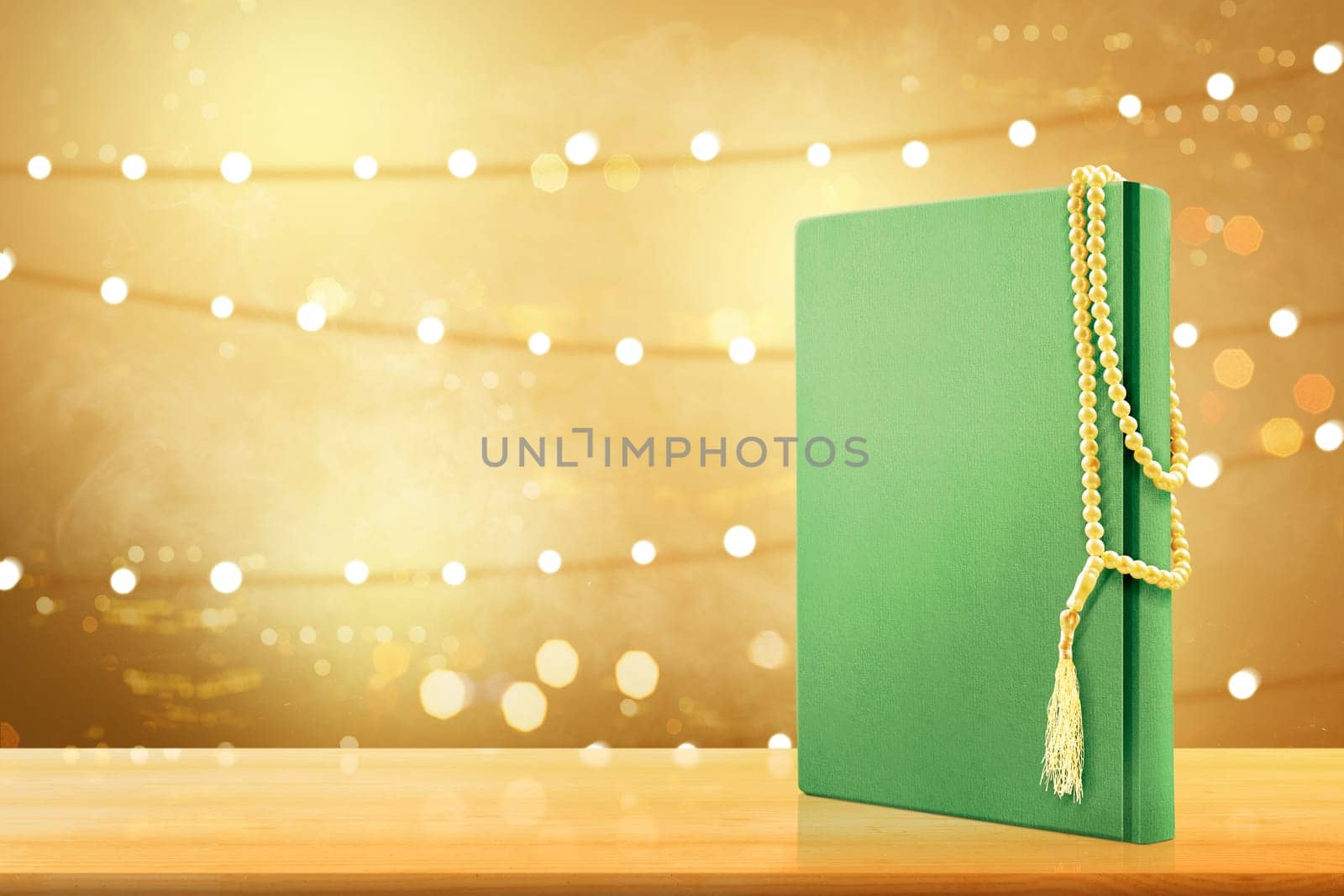 Quran and prayer beads on wooden table with blurry lights background
