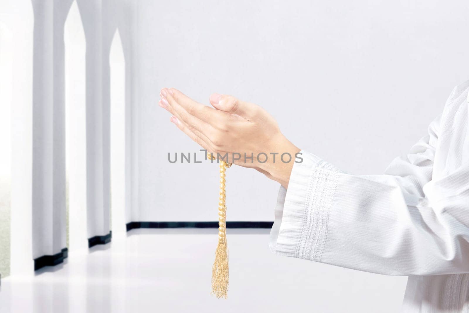 Muslim man praying with prayer beads on his hands in the mosque