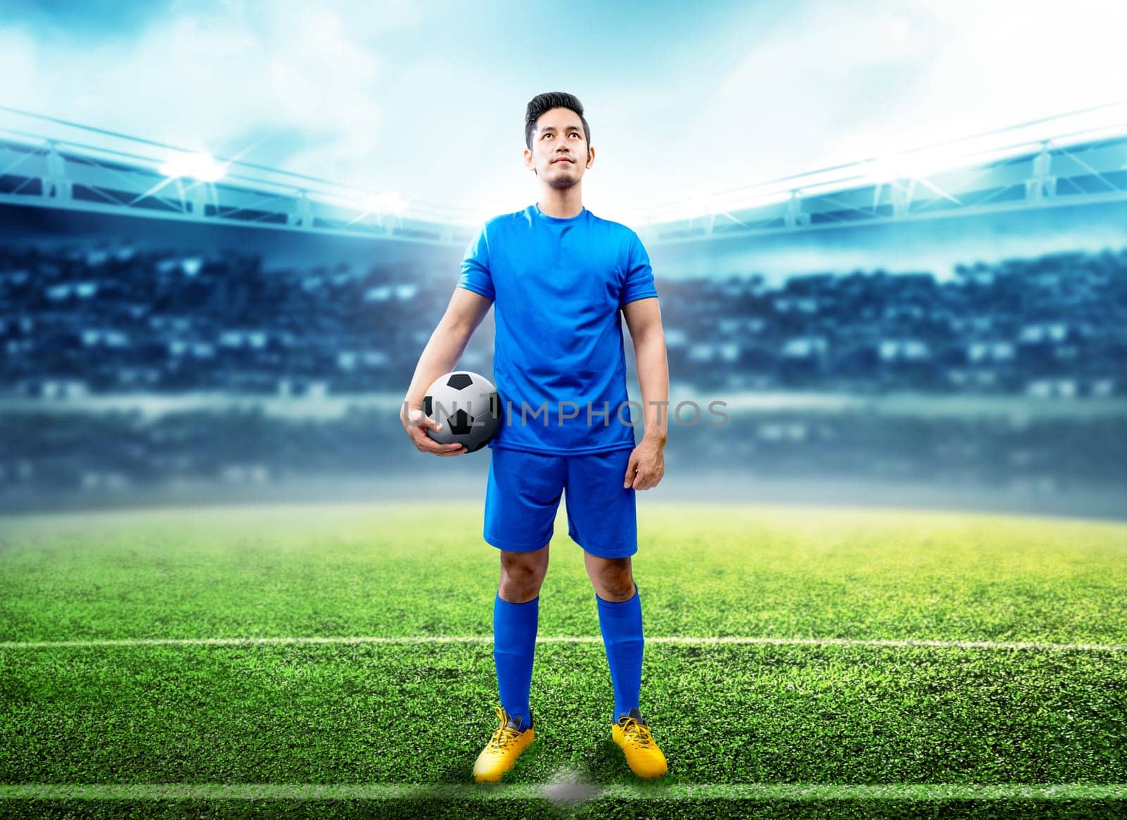 Asian football player man holding the ball in the middle of football field on stadium