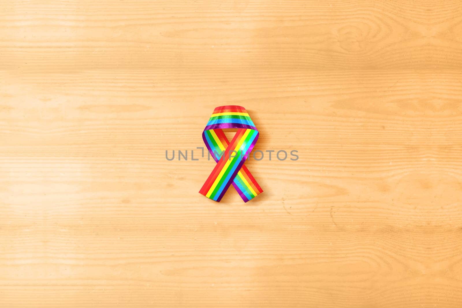 Ribbon with rainbow flag as a symbol of LGBT on wooden table. LGBT concept