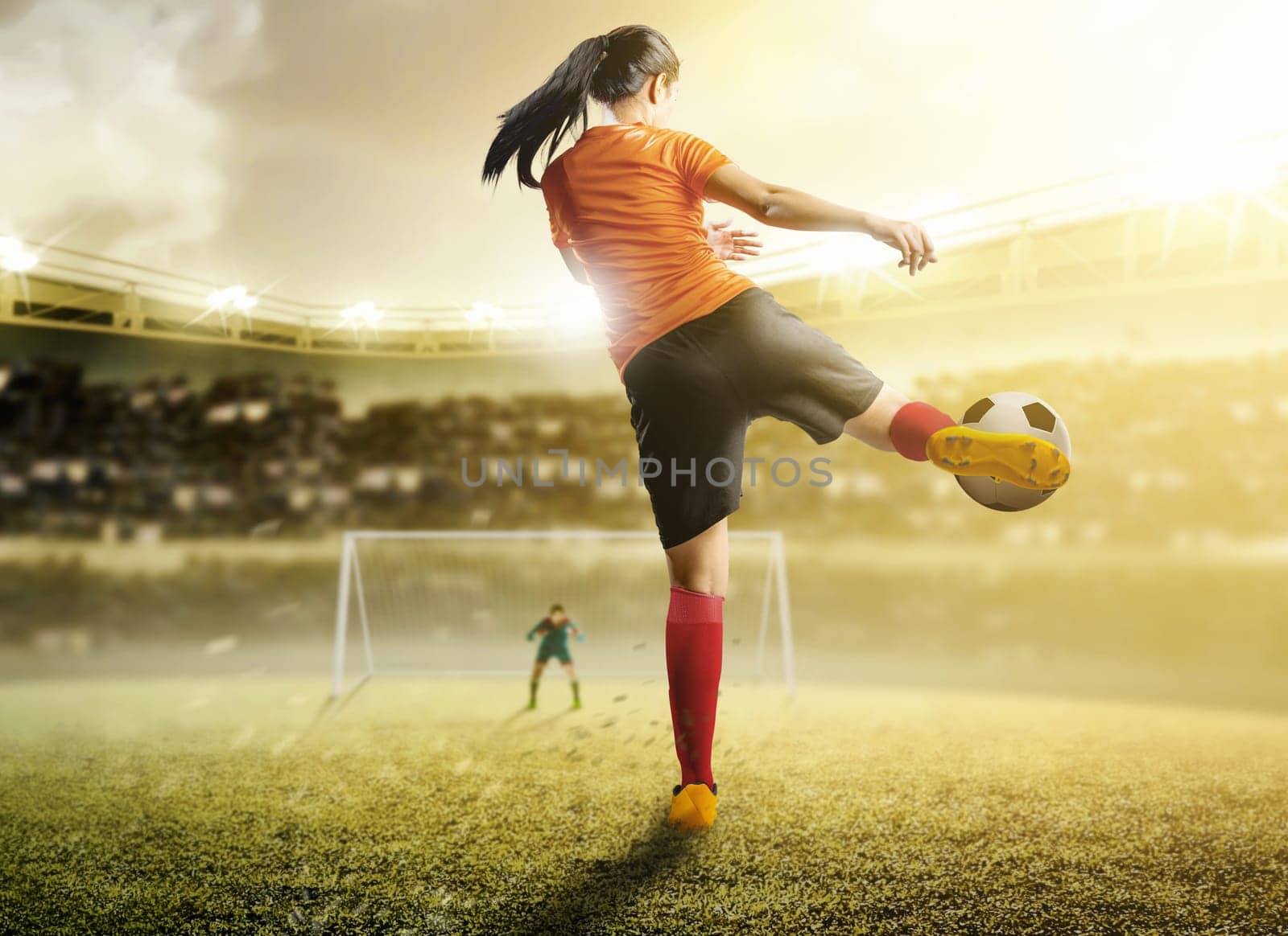 Rear view of asian football player woman in orange jersey kicking the ball in the penalty box on football field at stadium