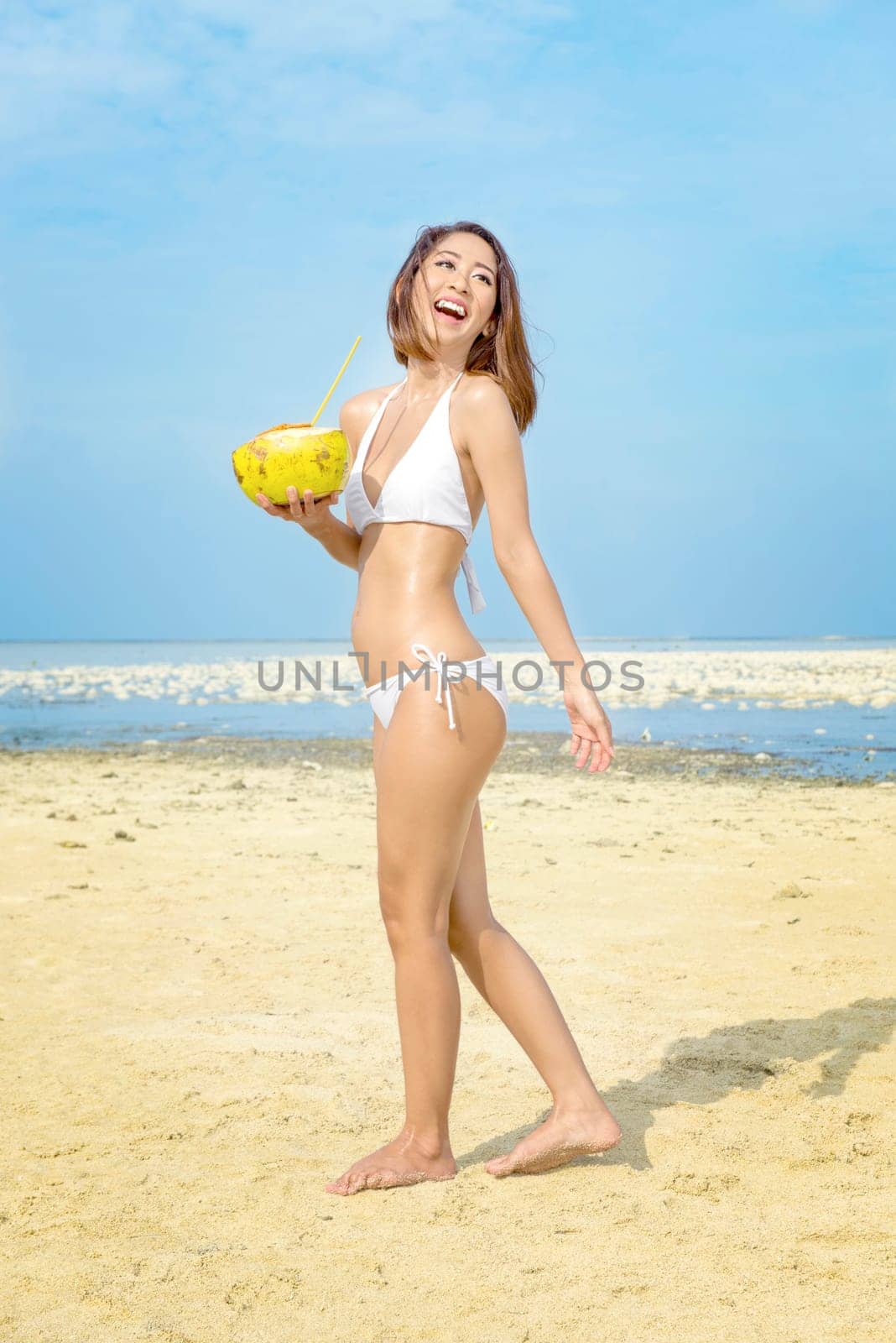 Asian sexy girl in bikini holding coconuts on the beach. Summer vacation