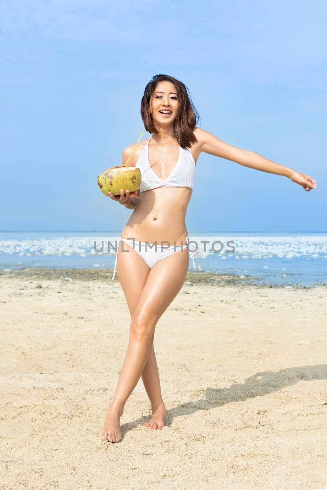 Asian sexy girl in bikini holding coconuts on the beach. Summer vacation